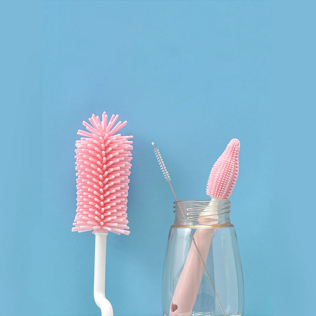Three silicone baby bottle brushes on a counter, including a main brush and a narrow straw cleaning brush.