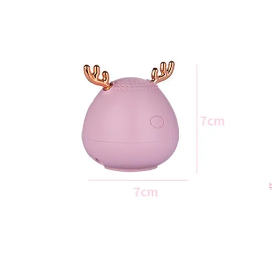 Small green portable Bluetooth speaker with USB cable on a white background.