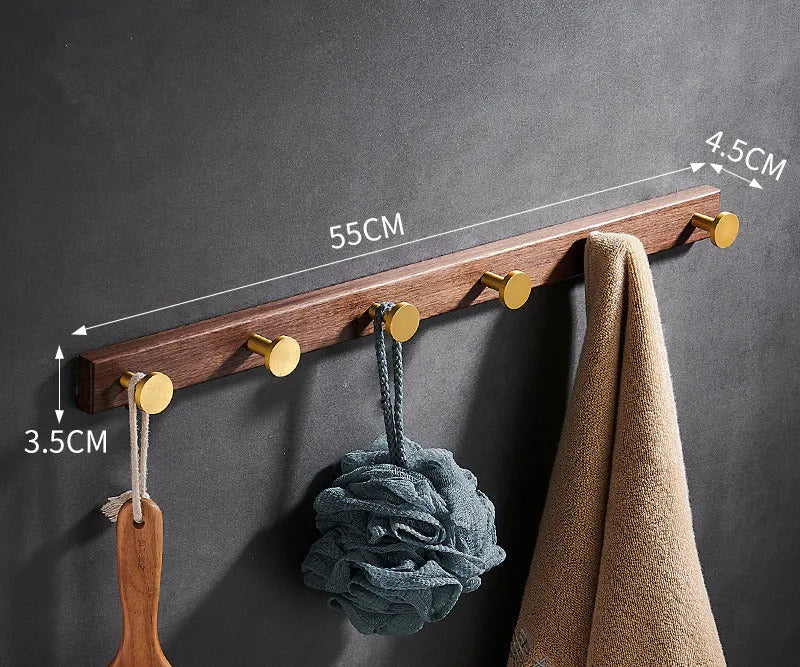 Set of black walnut aluminium clothes hooks with brass finish mounted on a perforated panel.