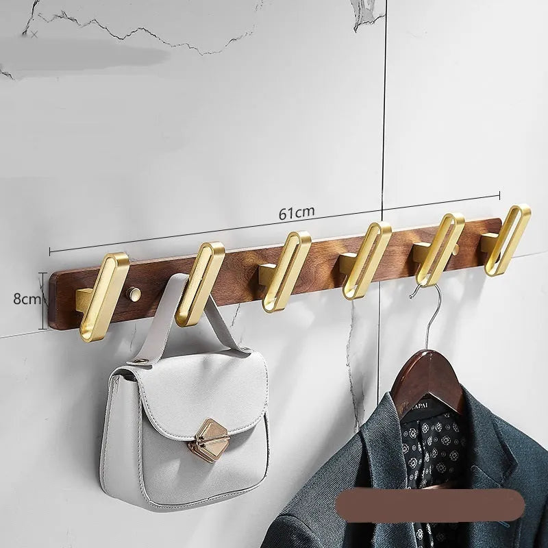Set of black walnut aluminium clothes hooks with brass finish mounted on a perforated panel.