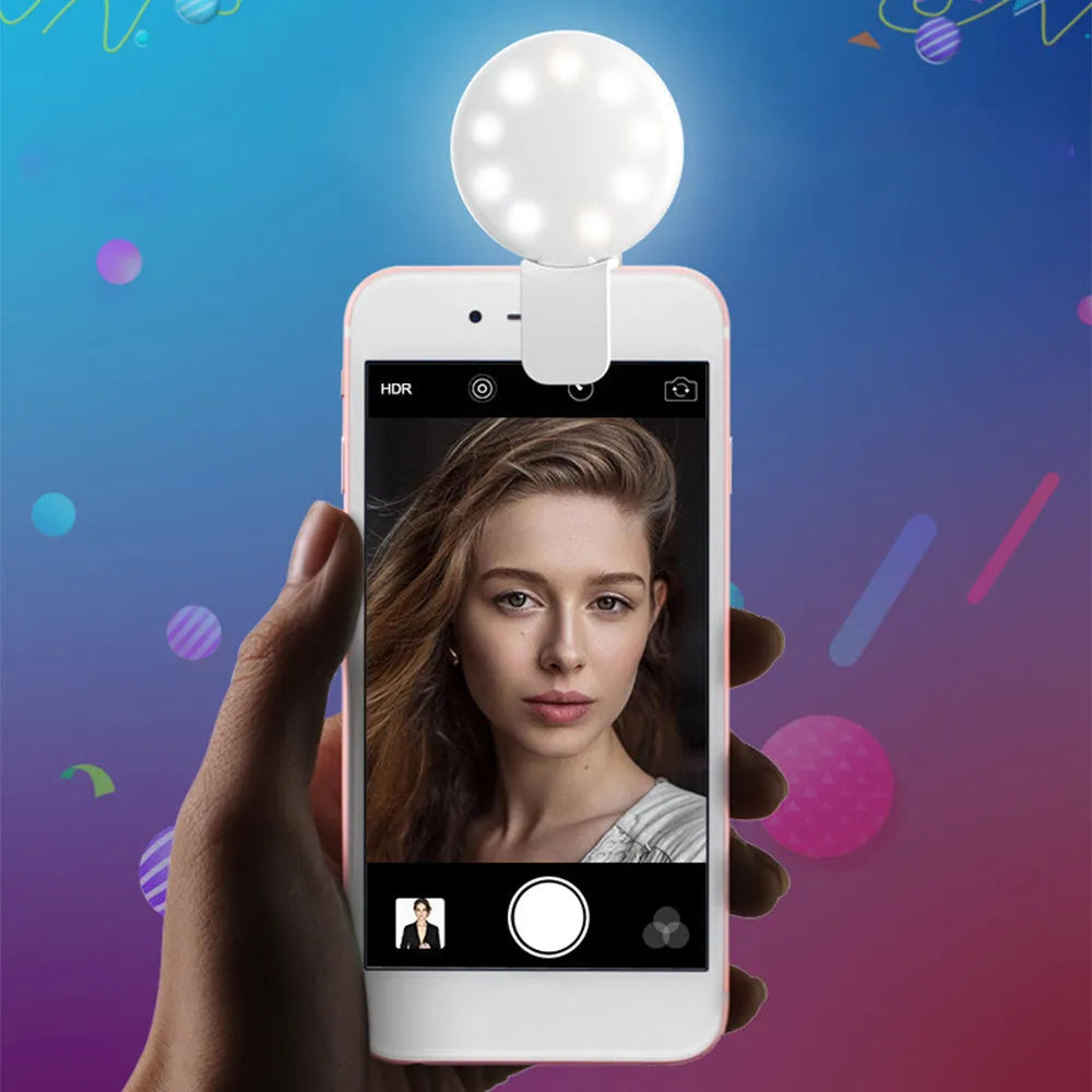Small round white clip-on LED fill light attached to a mobile phone for selfie photography.