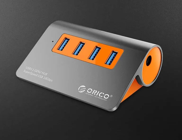 Dark grey aluminium USB hub with orange detailing showing four USB 3.1 ports and detachable cable