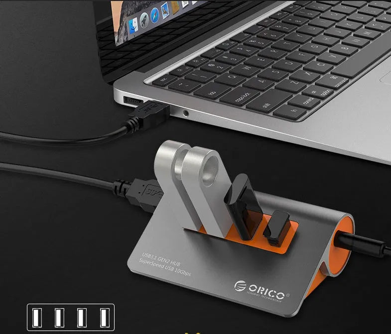 Dark grey aluminium USB hub with orange detailing showing four USB 3.1 ports and detachable cable