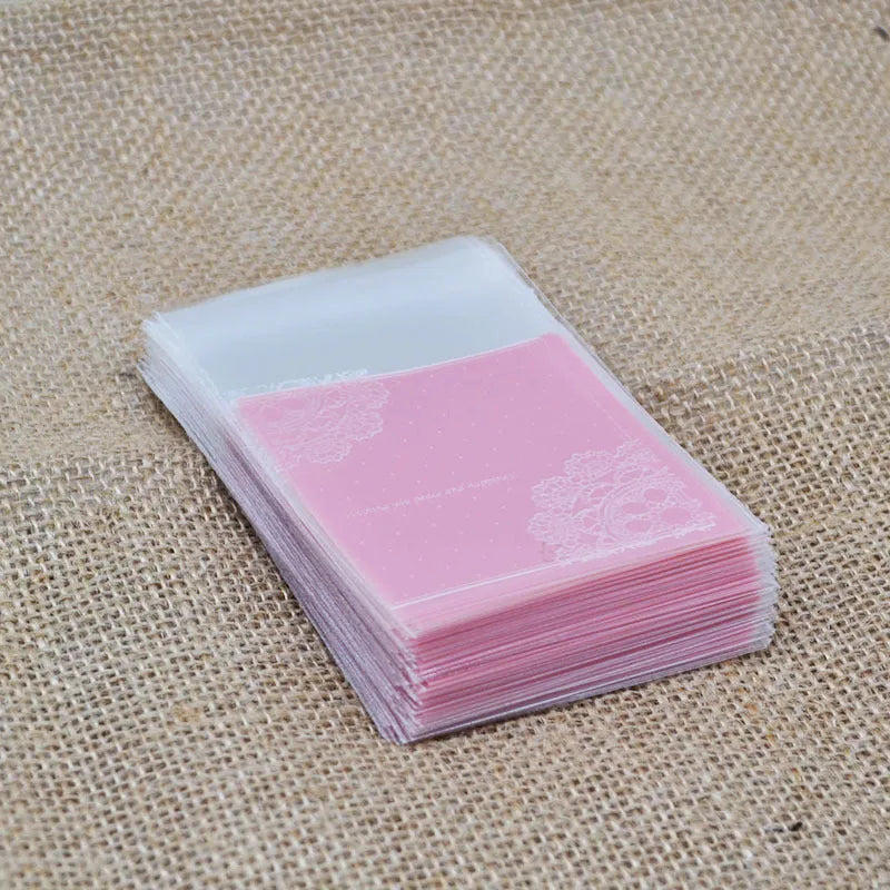 Pink self-adhesive plastic packaging bags in a pack, showing adhesive flap and size scale.