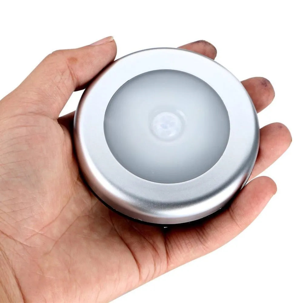 Round silver wireless motion sensor night light with battery operation for automatic LED illumination