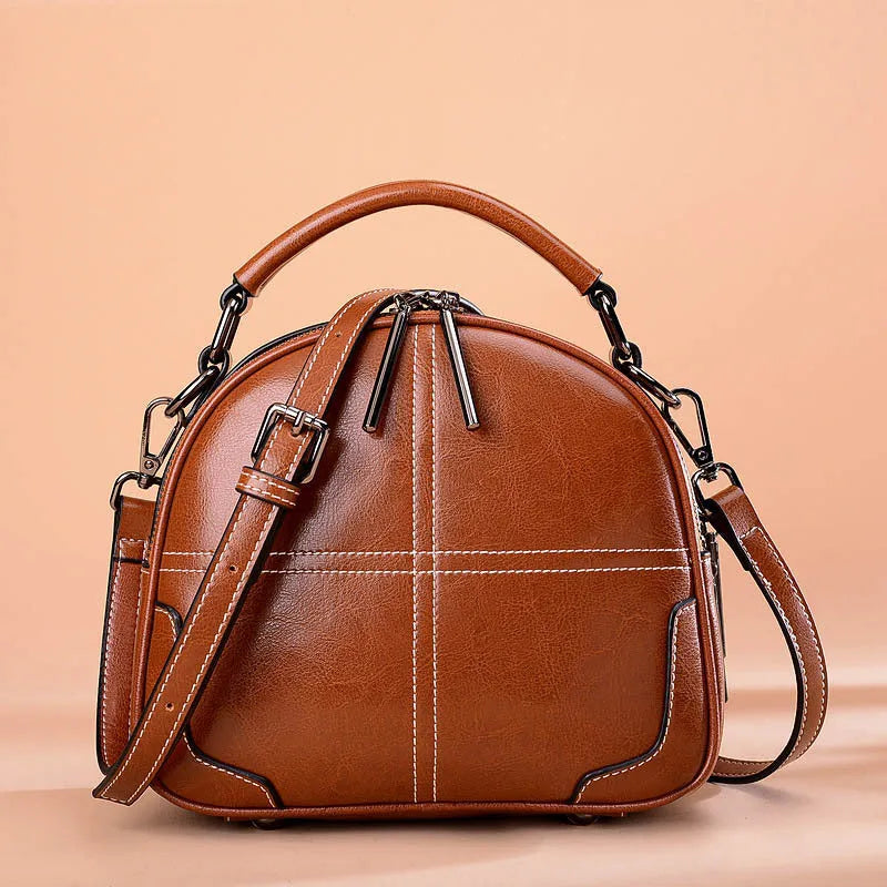 Round women's leather handbag with zipper and double soft handles in wine red colour.