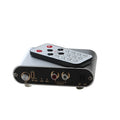 Silver aluminium audio source selector switch box with remote control on a dark surface.