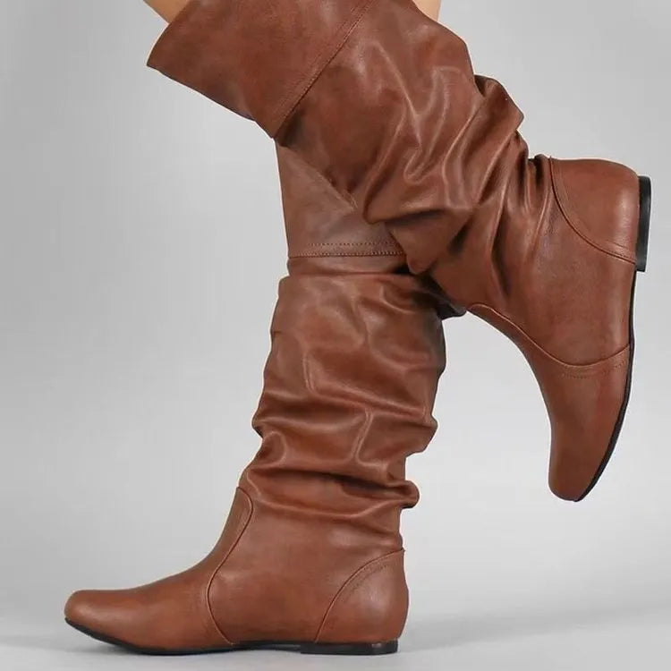 Women's flat heel slip-on boot in artificial PU with high cut and rubber sole.