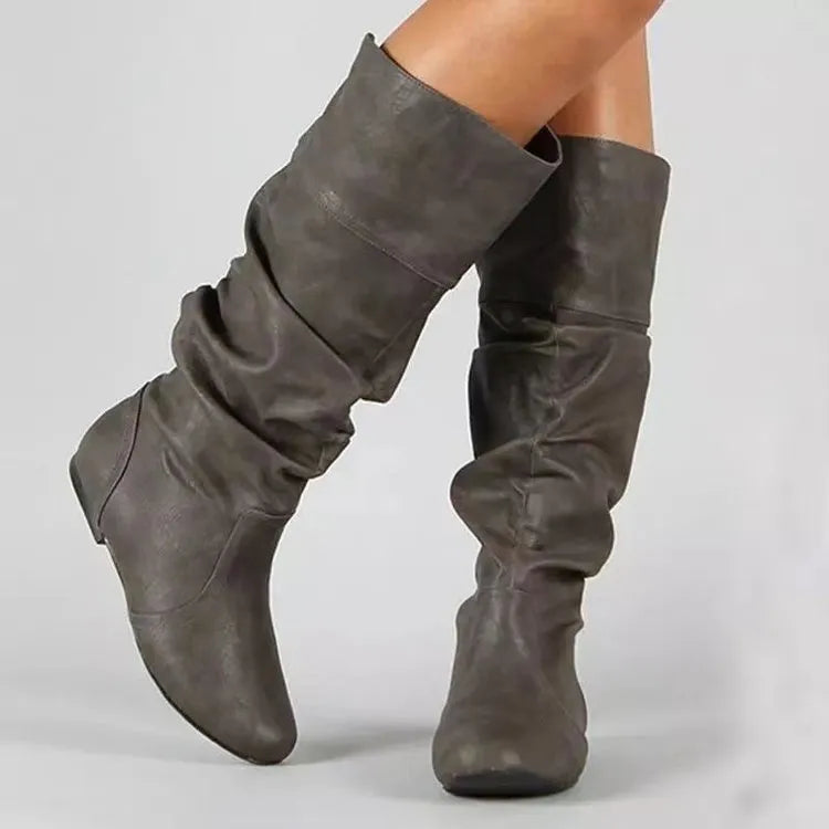 Women's flat heel slip-on boot in artificial PU with high cut and rubber sole.