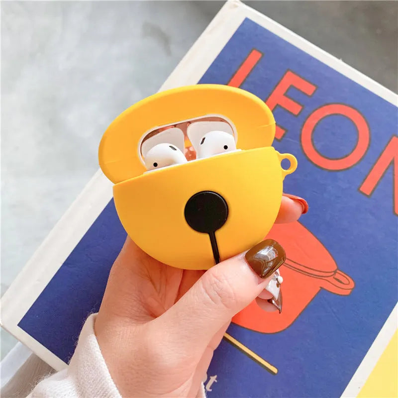Yellow silicone AirPods case with attached bell charm showing charging port and LED cutouts