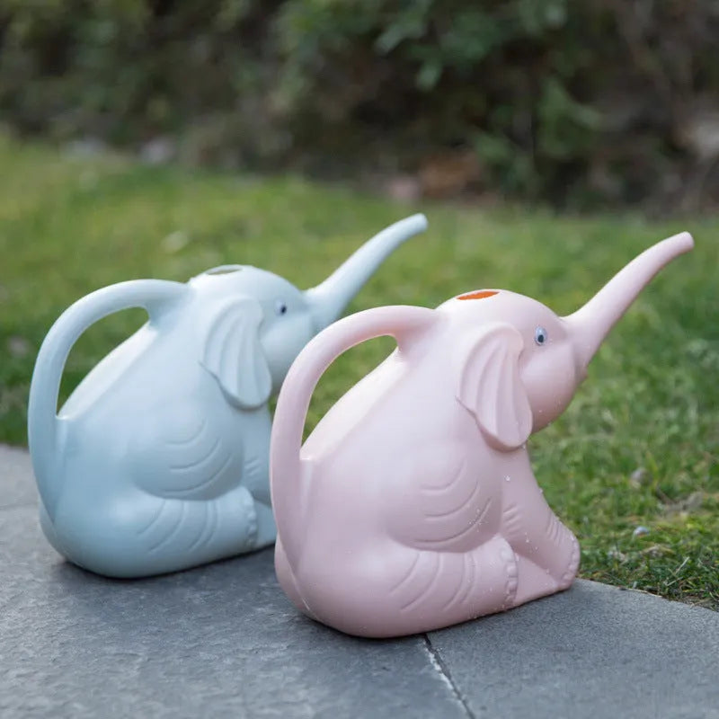 Pink baby elephant-shaped plastic watering can with a long spout on a wooden table.