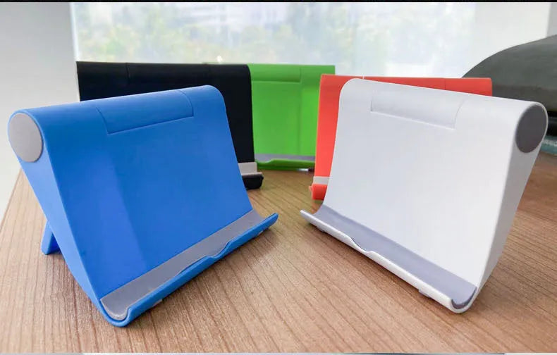 Black folding mobile phone stand holding a smartphone at an angle on a wooden table
