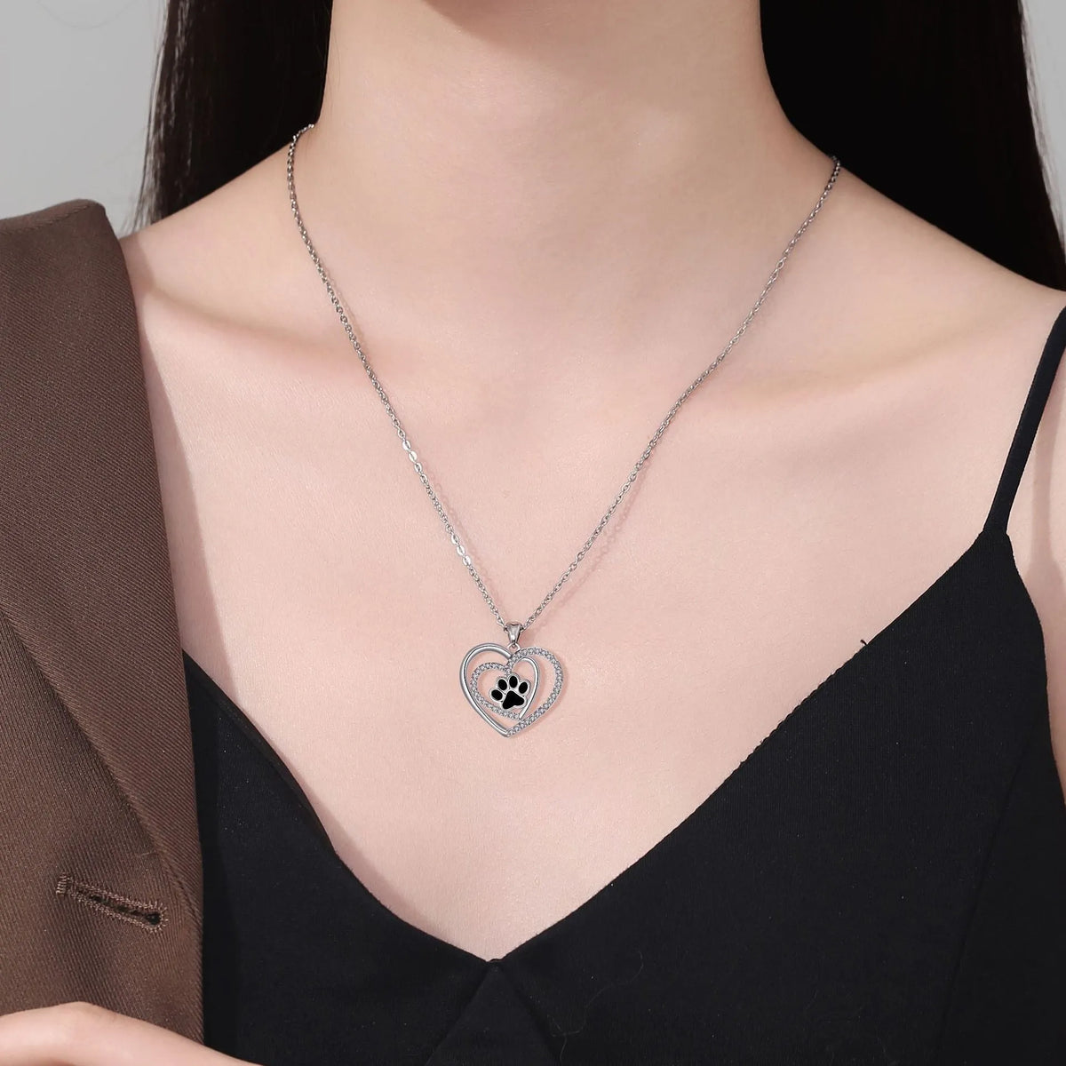 Women's copper necklace with a heart and dog paw prints pendant on a cross chain.