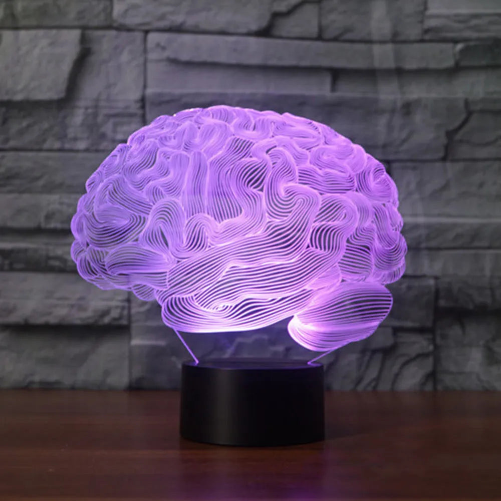 3D acrylic brain sculpture LED desk lamp with colourful illumination on a dark surface.