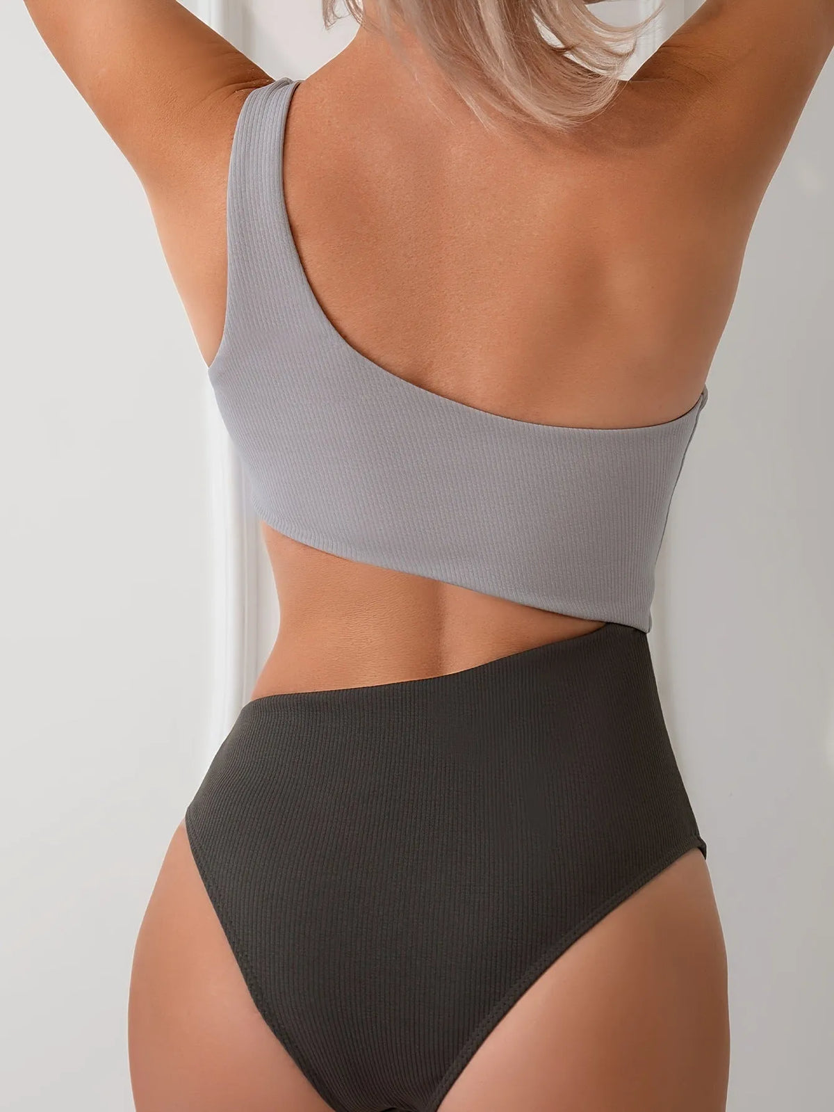 Light grey one-shoulder one-piece swimsuit on a mannequin, front view.