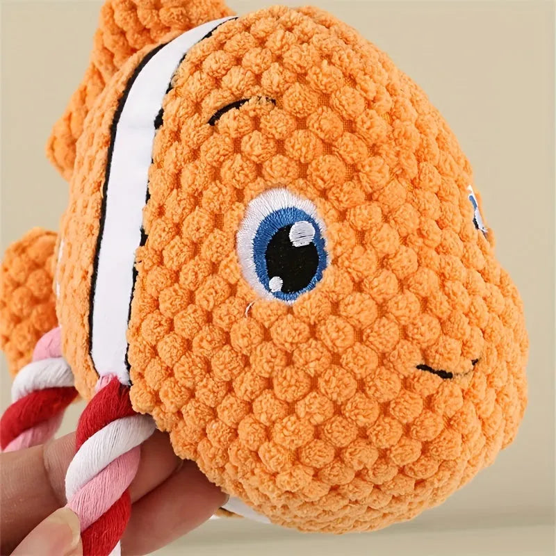 Grey, green, and orange turtle-shaped stuffed dog knot chewing toy on a plain background.