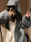 A woman wearing a thick, dark gray retro-style hooded cardigan with regular sleeves.