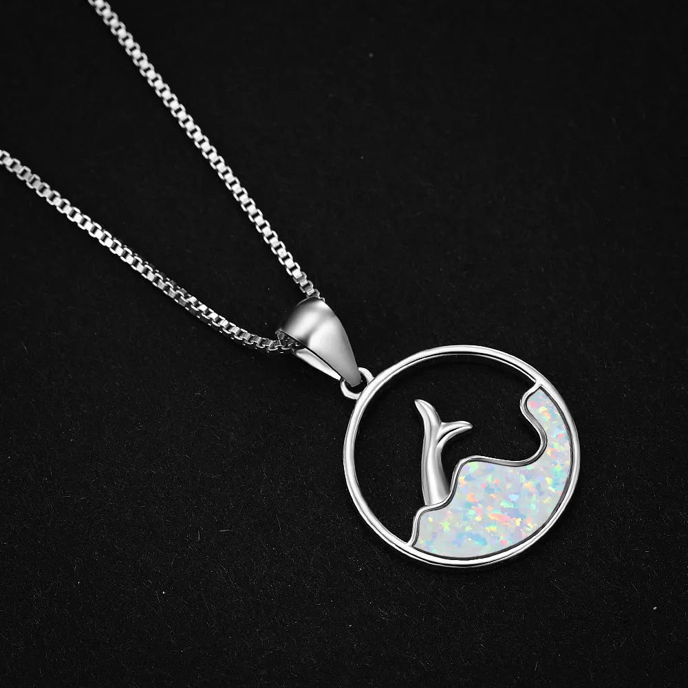 Close-up of a white gold electroplated geometric sea fishtail round pendant necklace on a model.