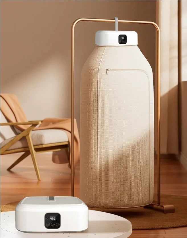 White cylindrical compact electric clothes dryer with remote control on a table.