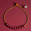 Close-up of a red cinnabar and beige Hetian jade geometric bracelet with a hand-woven adjustable strap.