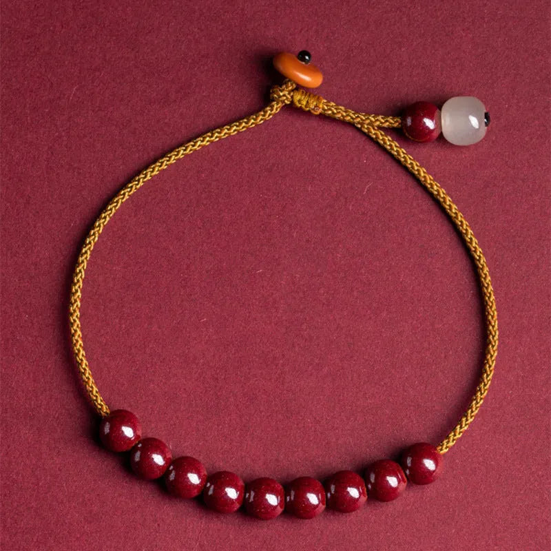 Close-up of a red cinnabar and beige Hetian jade geometric bracelet with a hand-woven adjustable strap.