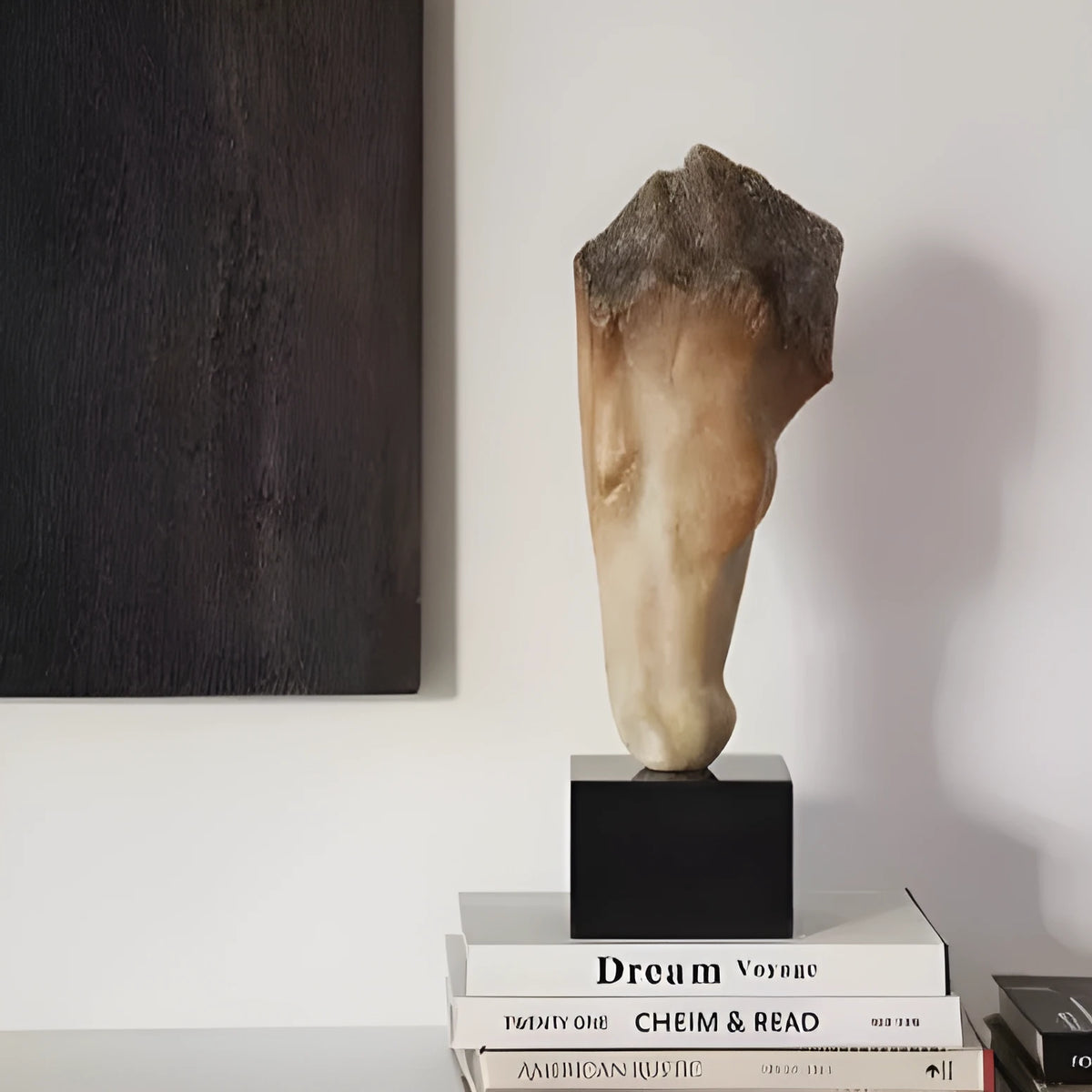 Tall abstract horse head sculpture with carved texture on a desk surface.