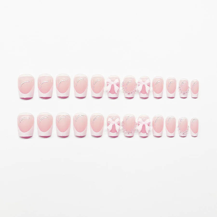 Short white French manicure false nails with decorative bow and tulip designs.