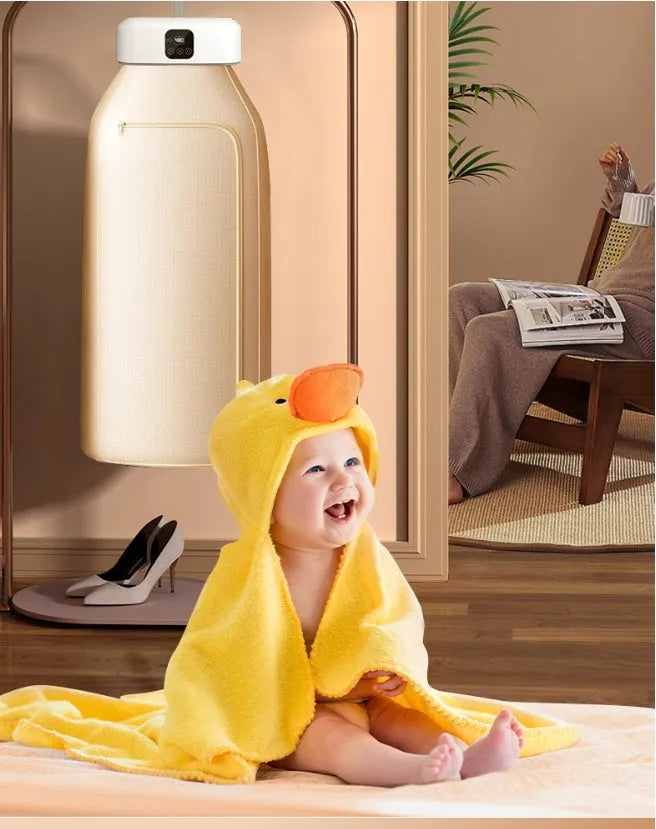 White cylindrical compact electric clothes dryer with remote control on a table.