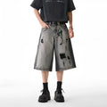 Women's loose-fit washed grey denim shorts with distressed hole details, cropped length.