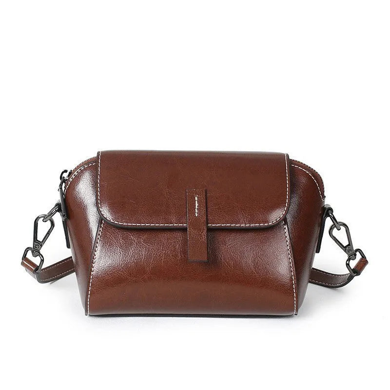 Women's brown shell-shaped messenger bag made of oil wax leather with a cross-body strap.