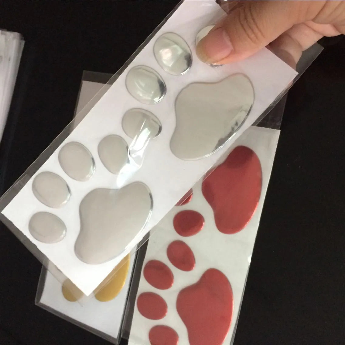 PVC car sticker with 3D hand-shaped brush texture forming dog footprints, in black, gold, red, or silver.