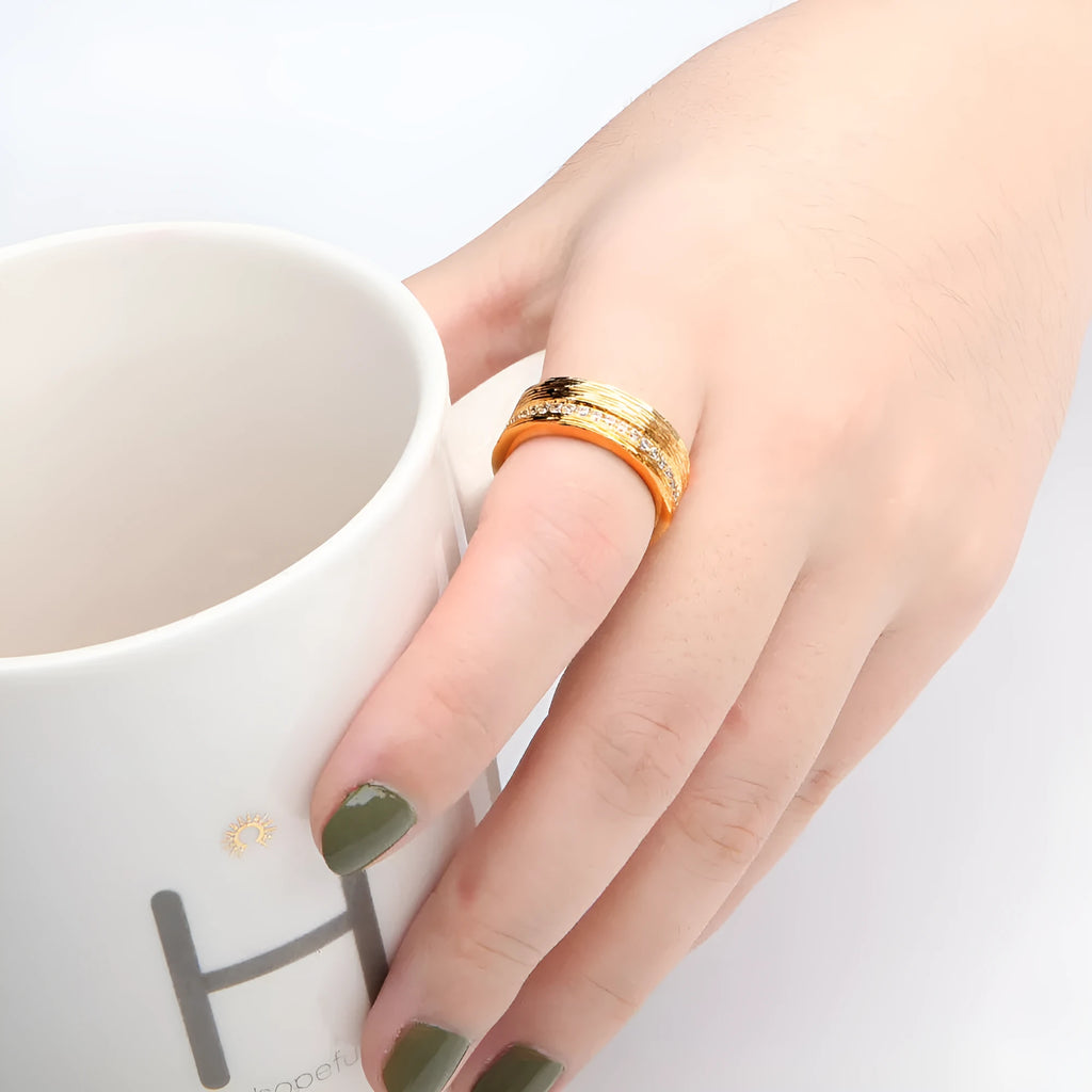 Gold-coloured geometric zircon ring for women on a plain background.