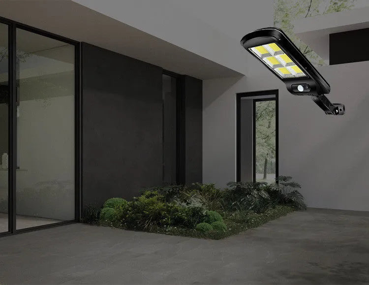 Black outdoor solar motion sensor security light mounted on a wall or fence post.