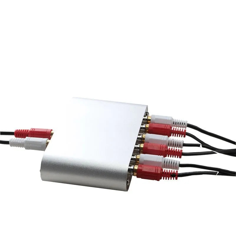 Silver aluminium audio source selector switch box with remote control on a dark surface.
