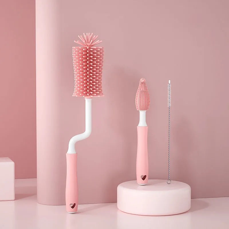 Three silicone baby bottle brushes on a counter, including a main brush and a narrow straw cleaning brush.