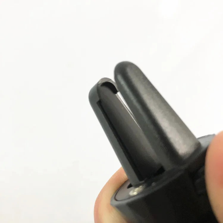 Black car phone holder clipped to car air vent with adjustable arms gripping a smartphone