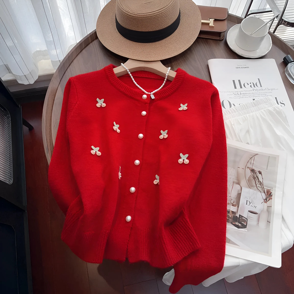 A pink cashmere blend ladies cardigan with beaded details, shown on a hanger.