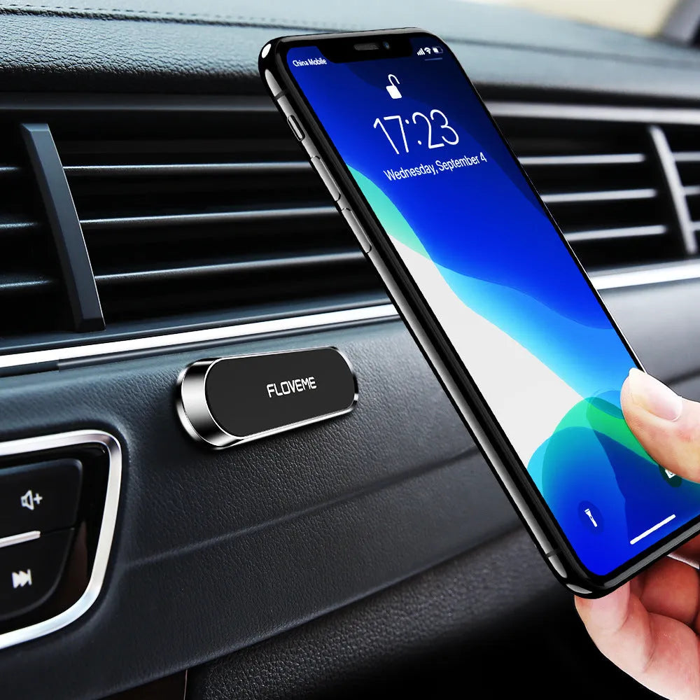Black magnetic car phone holder mounted on windscreen with silver iron sheet for mobile phone attachment