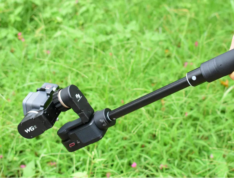 Black retractable aluminium selfie stick extended with smartphone attached and remote shutter in hand.