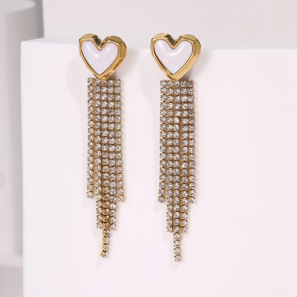 Women's gold heart and star shaped earrings with a diamond tassel detail on a white background.