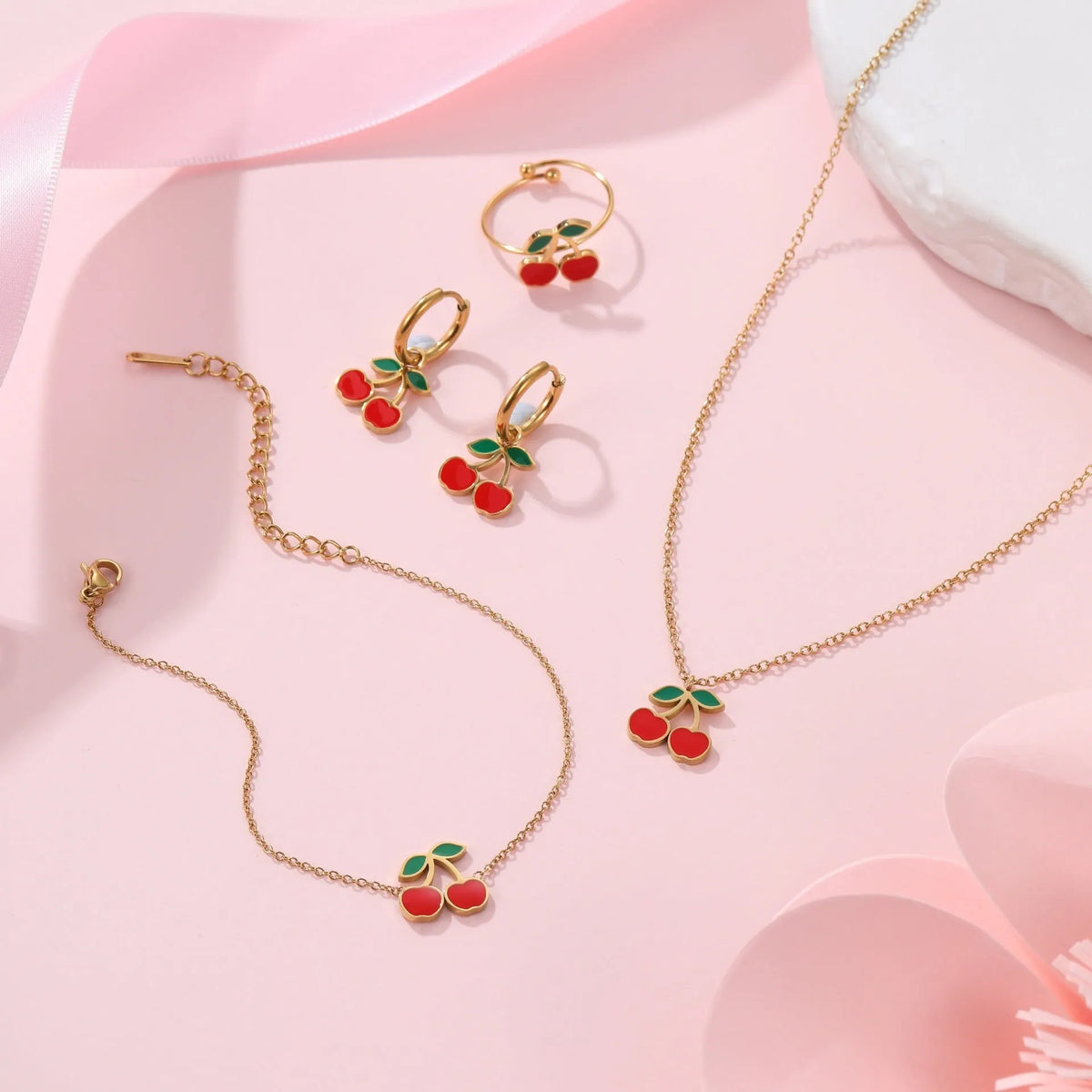 Cherry jewellery set showing necklace, bracelet, earrings, and ring with stainless steel construction and gold plating