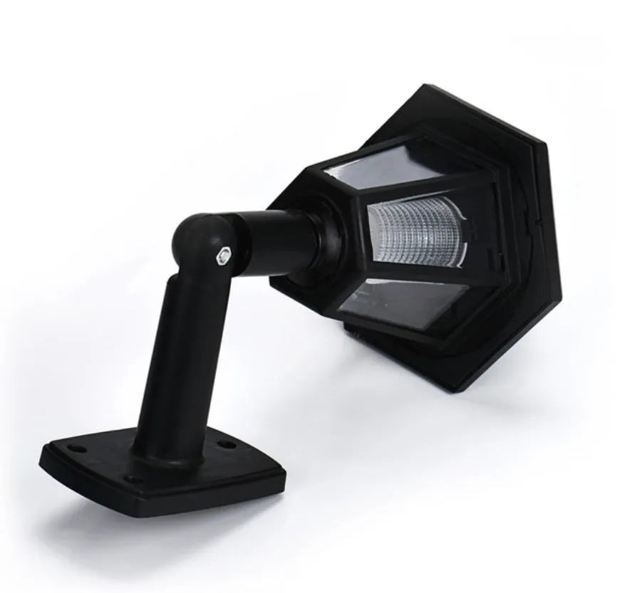 Black hexagonal solar-powered wall lamp for outdoor garden use, shown mounted on a fence