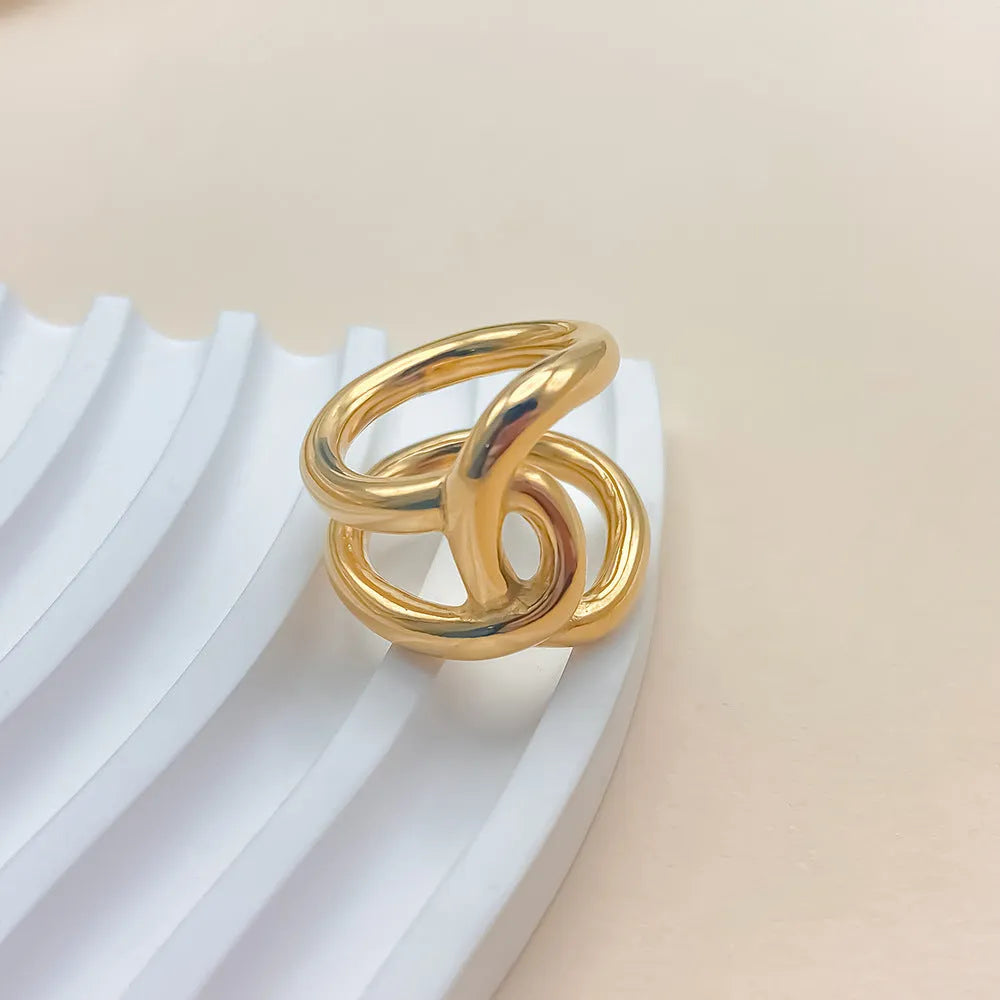 A gold-coloured geometric U-shaped ring with an adjustable opening and a knotted detail.