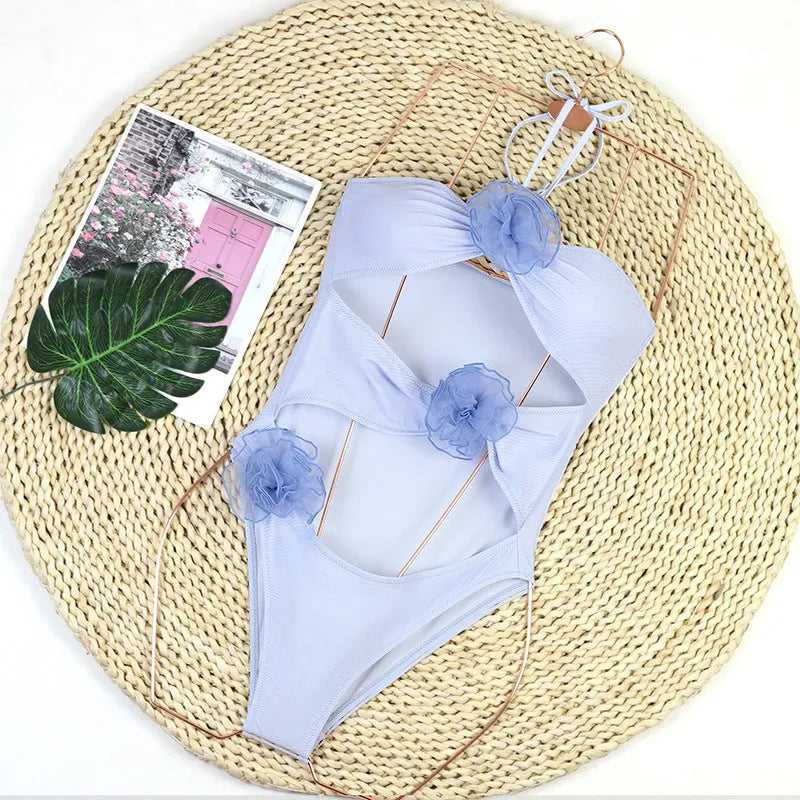 Women's black and blue striped one-piece swimsuit with 3D flower detailing.