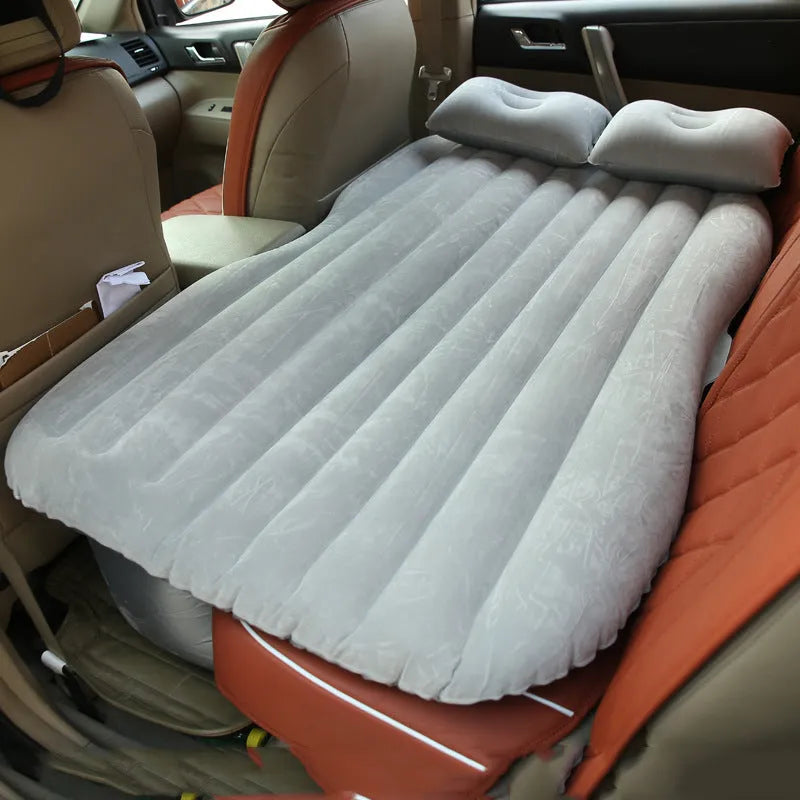 Universal inflatable car bed with flocked surface and pillows laid out in a car boot.