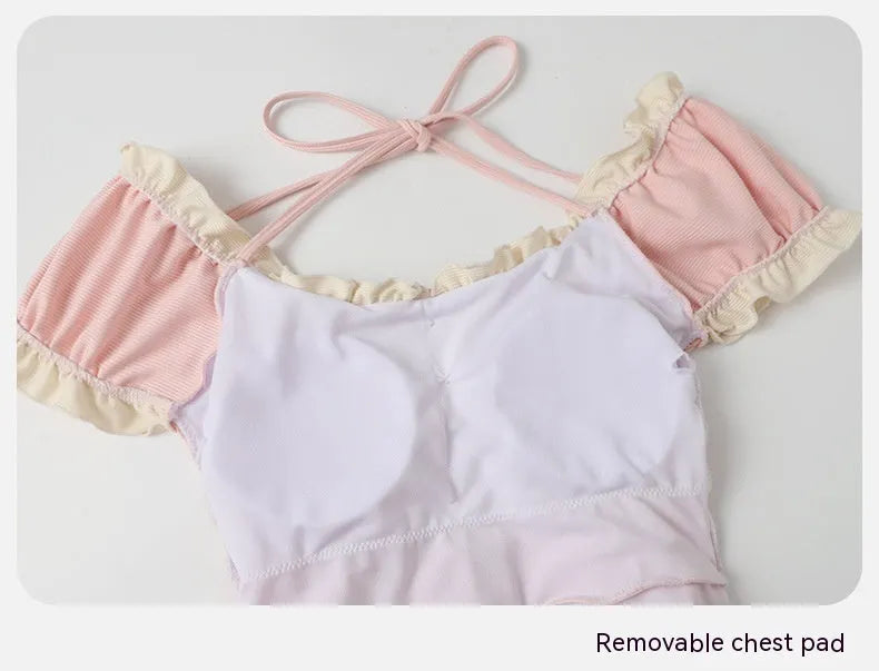 Pink women's conservative one-piece nylon swimsuit on a hanger.