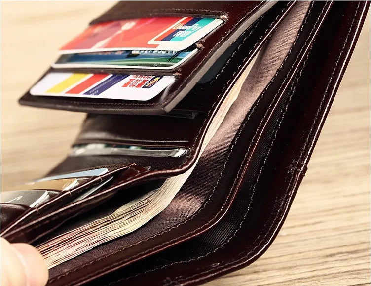 Men's brown leather wallet open to show card slots, ID window, coin pocket, and banknote fold.