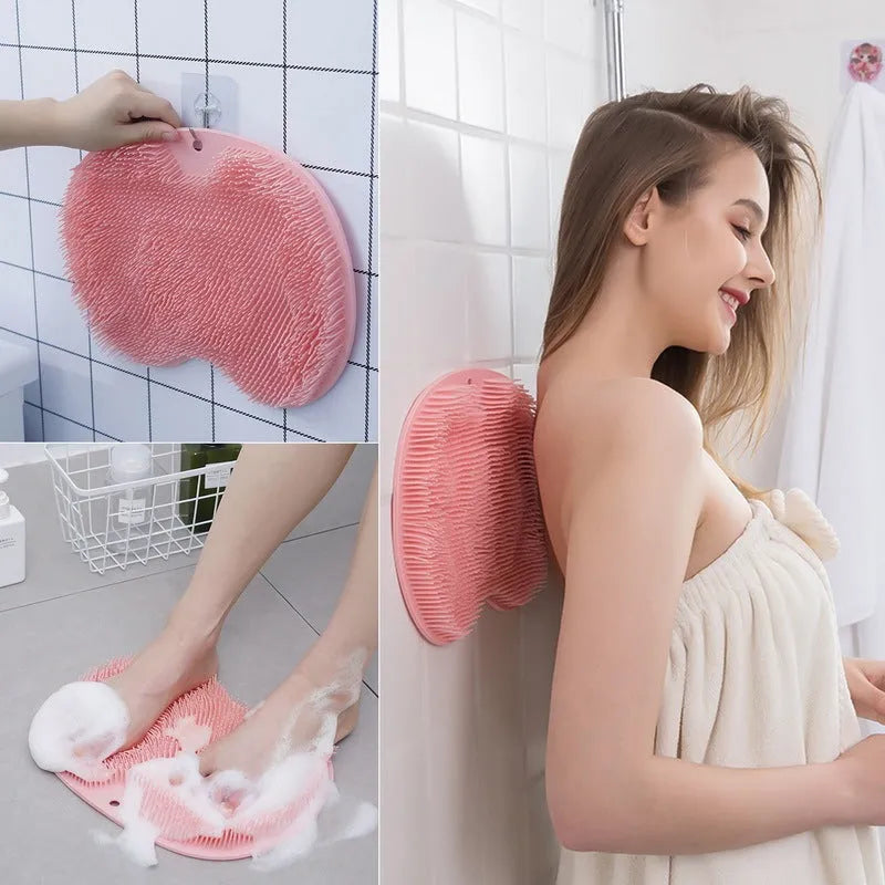 Orange silicone suction cup bath brush with bristles for back and foot massage on a bathroom floor.