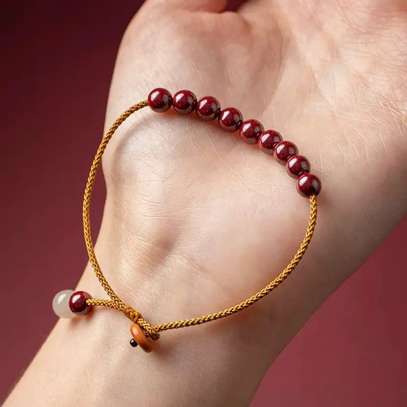 Close-up of a red cinnabar and beige Hetian jade geometric bracelet with a hand-woven adjustable strap.
