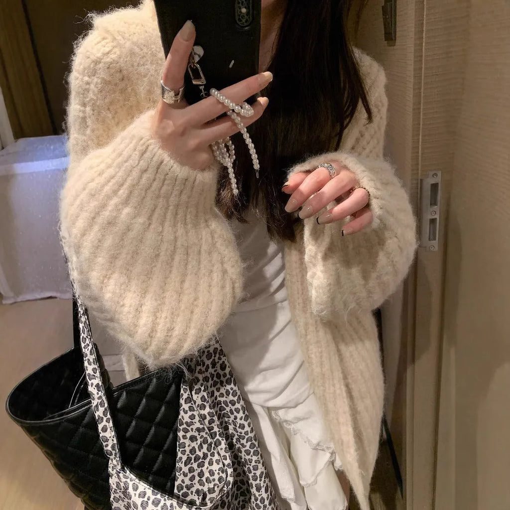 A woman wearing a thick, dark gray retro-style hooded cardigan with regular sleeves.